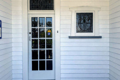 Imagen de puerta principal clásica con paredes blancas, suelo de madera pintada y suelo gris