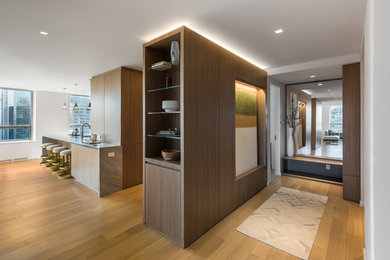 Imagen de distribuidor contemporáneo de tamaño medio con paredes blancas, suelo de madera clara, puerta simple y puerta de madera en tonos medios