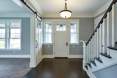 他の地域にある中くらいなトラディショナルスタイルのおしゃれな玄関ロビー (グレーの壁、濃色無垢フローリング、白いドア、茶色い床) の写真