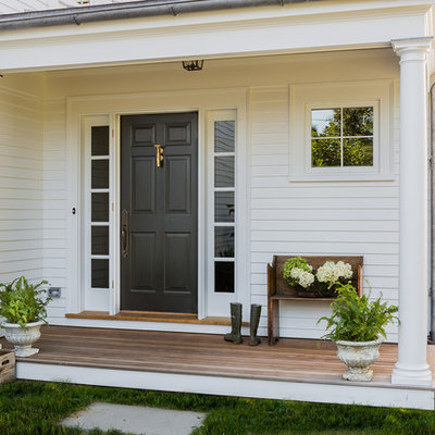 Entryway - traditional medium tone wood floor entryway idea in Boston with white walls and a black front door