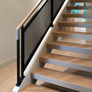 Ejemplo de distribuidor abovedado, moderno, de tamaño medio, con paredes beige, suelo de madera clara, puerta simple y suelo gris