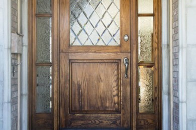 Imagen de puerta principal clásica de tamaño medio con paredes beige, suelo de cemento, puerta simple y puerta de madera en tonos medios