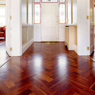 Exemple d'un hall d'entrée chic de taille moyenne avec un mur beige, un sol en bois brun, une porte simple et une porte blanche.