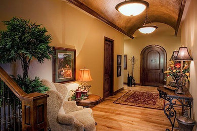 Cette photo montre une entrée chic avec un couloir, un mur beige, parquet clair, une porte simple et une porte en bois foncé.