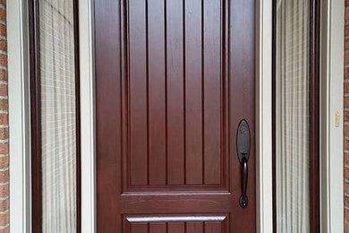 Diseño de puerta principal tradicional grande con paredes rojas, suelo de cemento, puerta simple y puerta de madera oscura