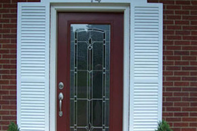 Imagen de puerta principal clásica de tamaño medio con paredes rojas, suelo de ladrillo, puerta simple y puerta roja