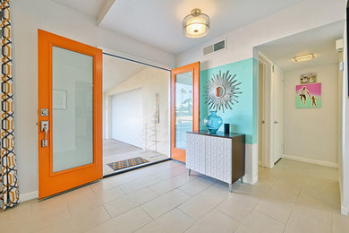 他の地域にある中くらいなミッドセンチュリースタイルのおしゃれな玄関ドア (白い壁、セラミックタイルの床、オレンジのドア、ベージュの床) の写真