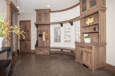 Example of a large mountain style ceramic tile and brown floor entryway design in Salt Lake City with beige walls and a medium wood front door