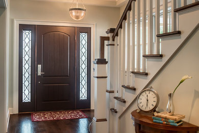 Ispirazione per un ingresso american style di medie dimensioni con pareti beige, parquet scuro, una porta singola e una porta marrone