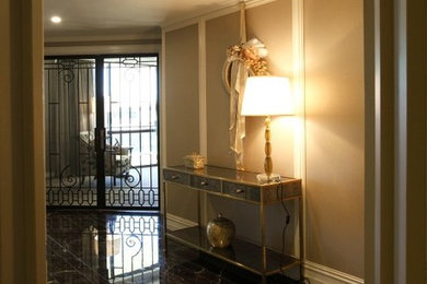 パースにある高級な中くらいなトラディショナルスタイルのおしゃれな玄関ラウンジ (ベージュの壁、大理石の床、白いドア、黒い床) の写真
