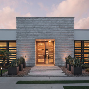 Immagine di una porta d'ingresso design con pareti bianche, pavimento in cemento, una porta a due ante, una porta in legno chiaro e pavimento grigio
