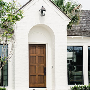Große Mediterrane Haustür mit weißer Wandfarbe, Backsteinboden, Einzeltür, hellbrauner Holztür und rotem Boden in Jacksonville