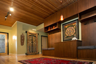 Idée de décoration pour un grand hall d'entrée design avec un mur vert, un sol en bois brun, une porte simple, une porte noire et un sol marron.