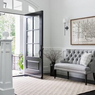 Idée de décoration pour un hall d'entrée tradition avec un mur blanc, un sol en bois foncé, une porte simple, une porte noire, un sol noir et boiseries.