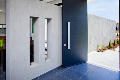 Aménagement d'une porte d'entrée moderne avec une porte noire et un sol bleu.
