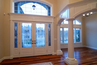 Huge elegant medium tone wood floor entryway photo in Newark with beige walls and a white front door