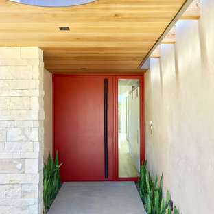 Idee per una grande porta d'ingresso minimalista con pareti beige, pavimento in cemento, una porta a pivot, una porta rossa e pavimento grigio