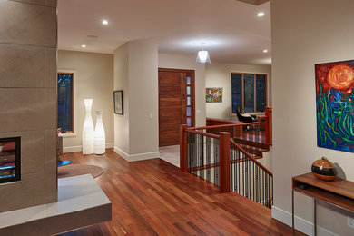 Foto de distribuidor minimalista con paredes beige, suelo de madera en tonos medios y puerta de madera en tonos medios