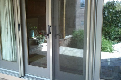 Modelo de puerta principal clásica de tamaño medio con paredes beige, suelo de cemento, puerta doble, puerta marrón y suelo beige