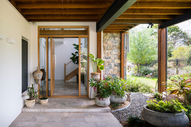 Diseño de puerta principal actual de tamaño medio con paredes blancas, suelo de travertino, puerta pivotante, puerta de madera clara y suelo gris