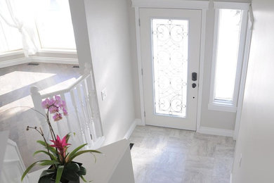 Entryway - mid-sized transitional marble floor entryway idea in Calgary with gray walls and a white front door