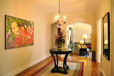 Ejemplo de entrada clásica de tamaño medio con paredes beige y suelo de madera en tonos medios