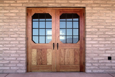 フェニックスにある高級な広いラスティックスタイルのおしゃれな玄関ドア (茶色い壁、コンクリートの床、木目調のドア) の写真