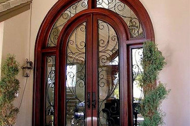 Modelo de puerta principal mediterránea grande con puerta doble, puerta de madera oscura, paredes beige y suelo de piedra caliza