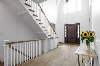 Large transitional light wood floor and brown floor entryway photo in New York with white walls and a dark wood front door