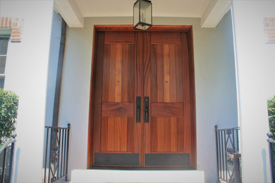 Ejemplo de entrada tradicional con puerta doble y puerta de madera en tonos medios