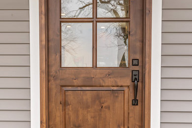 Стильный дизайн: входная дверь в стиле кантри с серыми стенами, одностворчатой входной дверью и входной дверью из дерева среднего тона - последний тренд