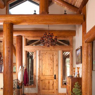 Idee per un grande ingresso rustico con pavimento in cemento, una porta singola, una porta in legno chiaro e pareti beige