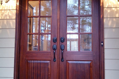 アトランタにある高級な広いおしゃれな玄関ドア (ベージュの壁、レンガの床、濃色木目調のドア、赤い床) の写真