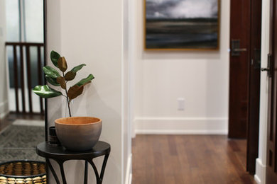 Example of a huge minimalist medium tone wood floor and brown floor entryway design in Vancouver with white walls and a brown front door