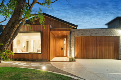 Стильный дизайн: большая узкая прихожая в стиле модернизм с коричневыми стенами, светлым паркетным полом, одностворчатой входной дверью, входной дверью из дерева среднего тона и коричневым полом - последний тренд