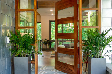 Example of a mid-sized beach style concrete floor entryway design in Charlotte with metallic walls and a medium wood front door