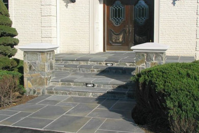 Example of a slate floor entryway design in DC Metro with white walls and a brown front door