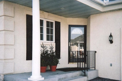 Diseño de puerta principal de tamaño medio con paredes marrones, suelo de cemento, puerta simple y puerta blanca