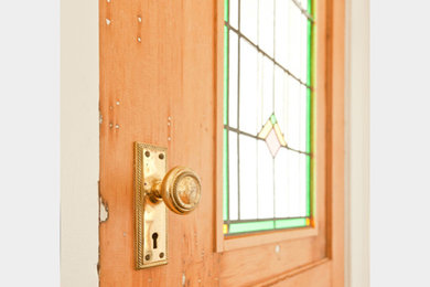 Diseño de entrada de estilo americano con suelo de madera clara y puerta simple