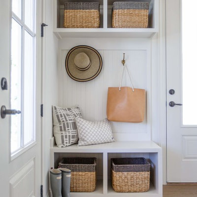 Mudroom - coastal medium tone wood floor mudroom idea in Jacksonville with white walls and a glass front door