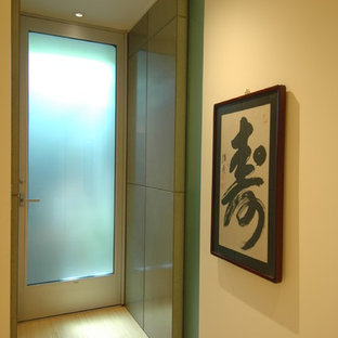 Cette image montre un petit vestibule minimaliste avec un mur jaune, un sol en bambou, une porte simple et une porte en verre.