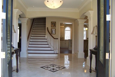 This is an example of a large classic foyer in Cleveland with beige walls, a double front door, a black front door, marble flooring and feature lighting.