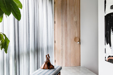 Imagen de entrada contemporánea con paredes blancas, puerta simple, puerta de madera clara y suelo gris
