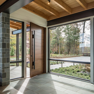 Idee per un grande ingresso design con pareti bianche, pavimento in pietra calcarea, una porta singola, una porta in legno bruno, pavimento grigio e pareti in legno