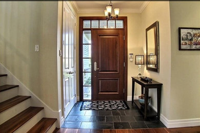 Imagen de puerta principal actual de tamaño medio con paredes beige, suelo de pizarra, puerta de madera en tonos medios y suelo negro