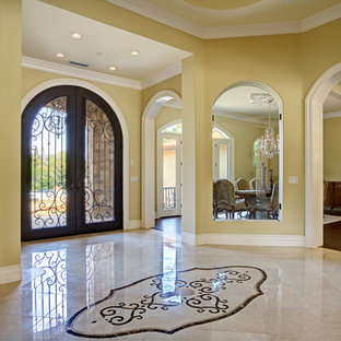 Example of a huge classic marble floor entryway design in San Francisco with yellow walls and a metal front door