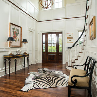 Imagen de distribuidor clásico renovado, grande, con suelo de madera oscura, puerta simple, puerta de madera oscura, paredes amarillas y suelo marrón