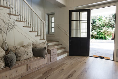 This is an example of a medium sized traditional front door in Los Angeles with white walls, light hardwood flooring, a single front door and a black front door.