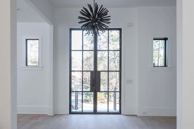 Example of a large transitional light wood floor entryway design in Atlanta with white walls and a black front door