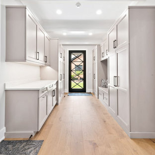 Cette image montre une grand entrée traditionnelle avec un vestiaire, un mur gris, un sol en bois clair, une porte simple, une porte blanche, un sol marron et un plafond à caissons.